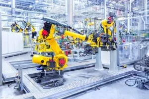 Brazos robóticos amarillos ensamblan componentes automotrices en una planta de manufactura automatizada en México.