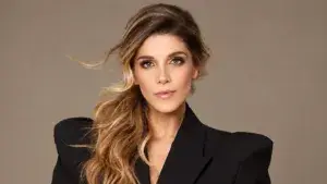 Retrato de Natalia Alcocer con saco negro y cabello ondulado sobre un hombro, frente a un fondo beige.