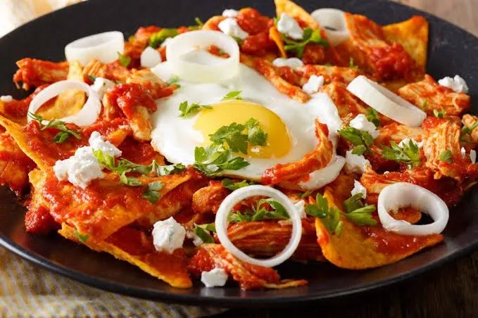 Chilaquiles mexicanos con salsa, queso y crema, un desayuno tradicional popular en Chihuahua.